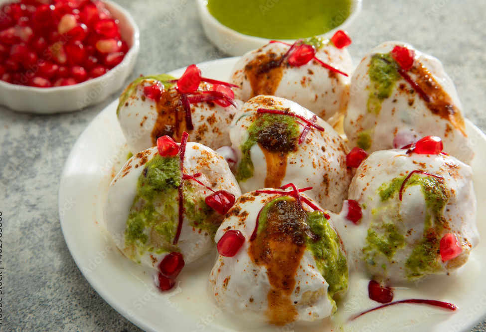 dahi vada or dahi bhalla a popular indian snack is fried lentil dumplings topped with curd sweet and green chutney and spices