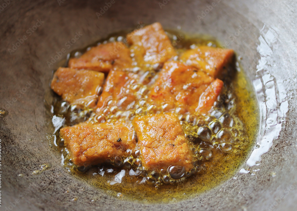 cakes of dhoka r dal being fried in a frying pan in mustard oil for cooking dhokar dalna a popular bengali recipe