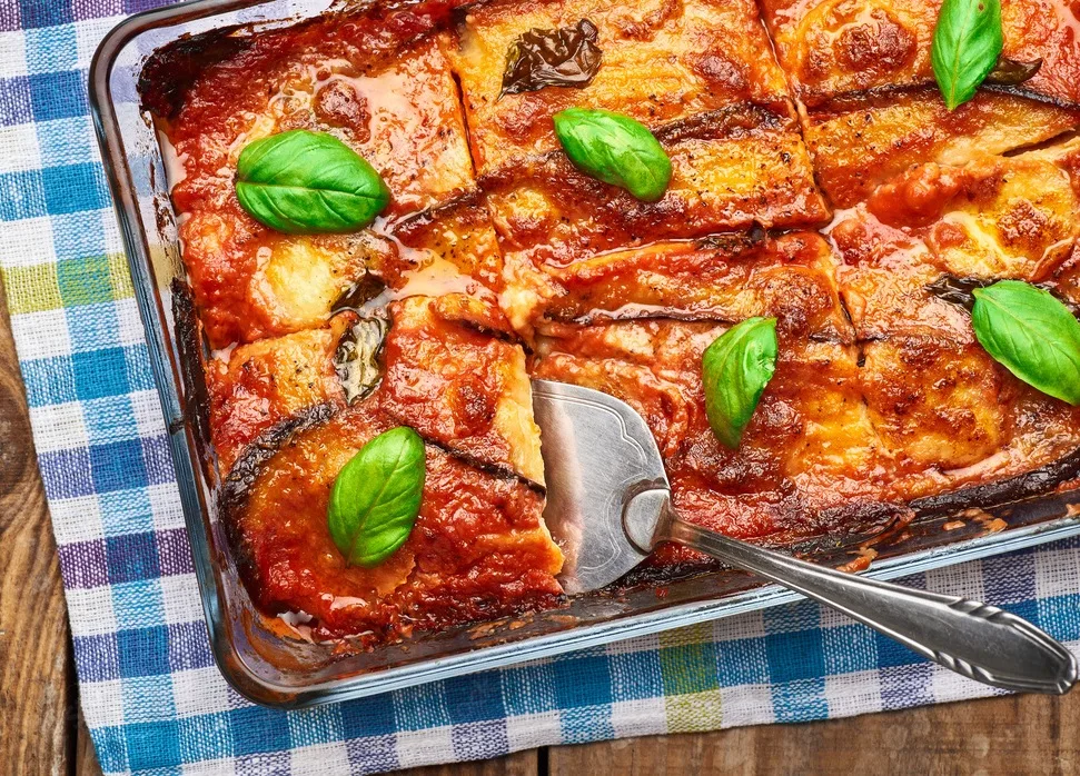 italian traditional eggplant parmigiana pie with fresh basil and mozzarella cheese.