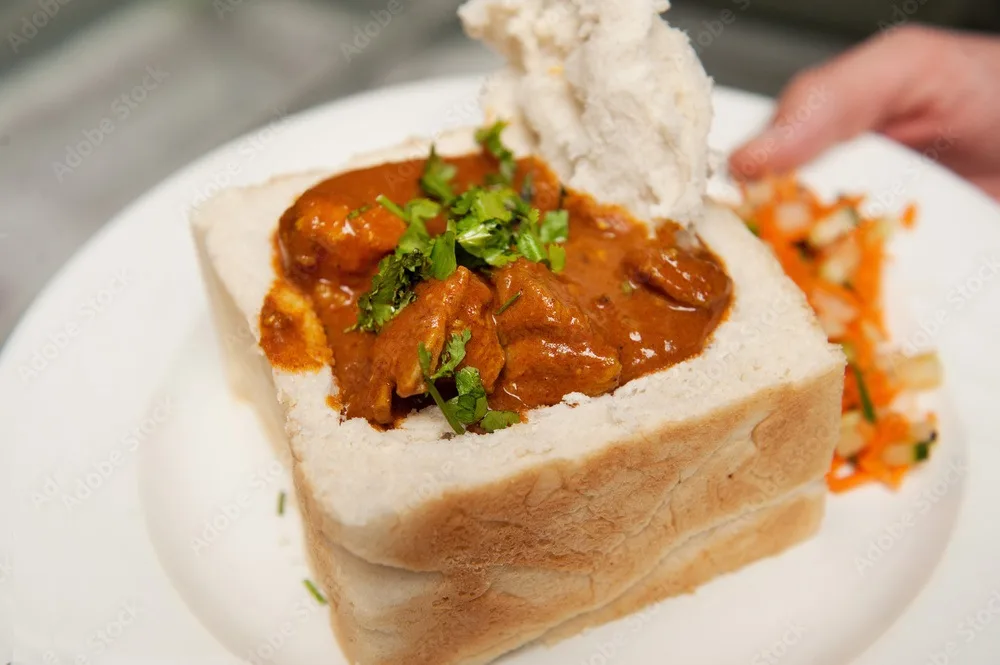 a traditional south african bunny chow, indian curry served in a hollowed out loaf of bread. durban south africa.