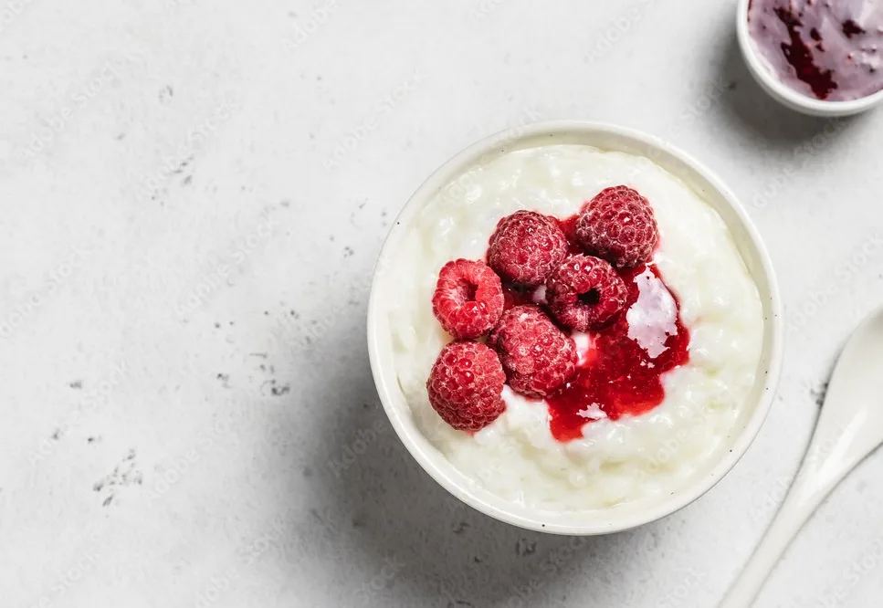 coconut milk rice pudding in a bowl with frozen raspberry