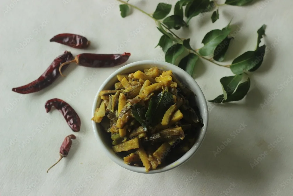 raw banana slices with shallots and spices. the raw banana slices are thin and long. popular side dish for meals in kerala